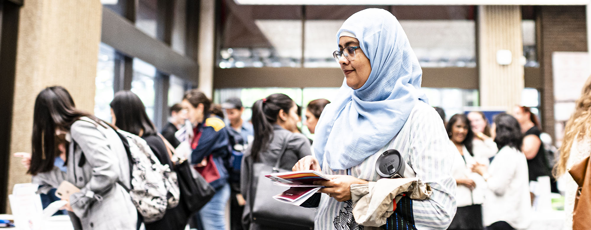 A student attending OISE Orientation and holding a mug and papers.